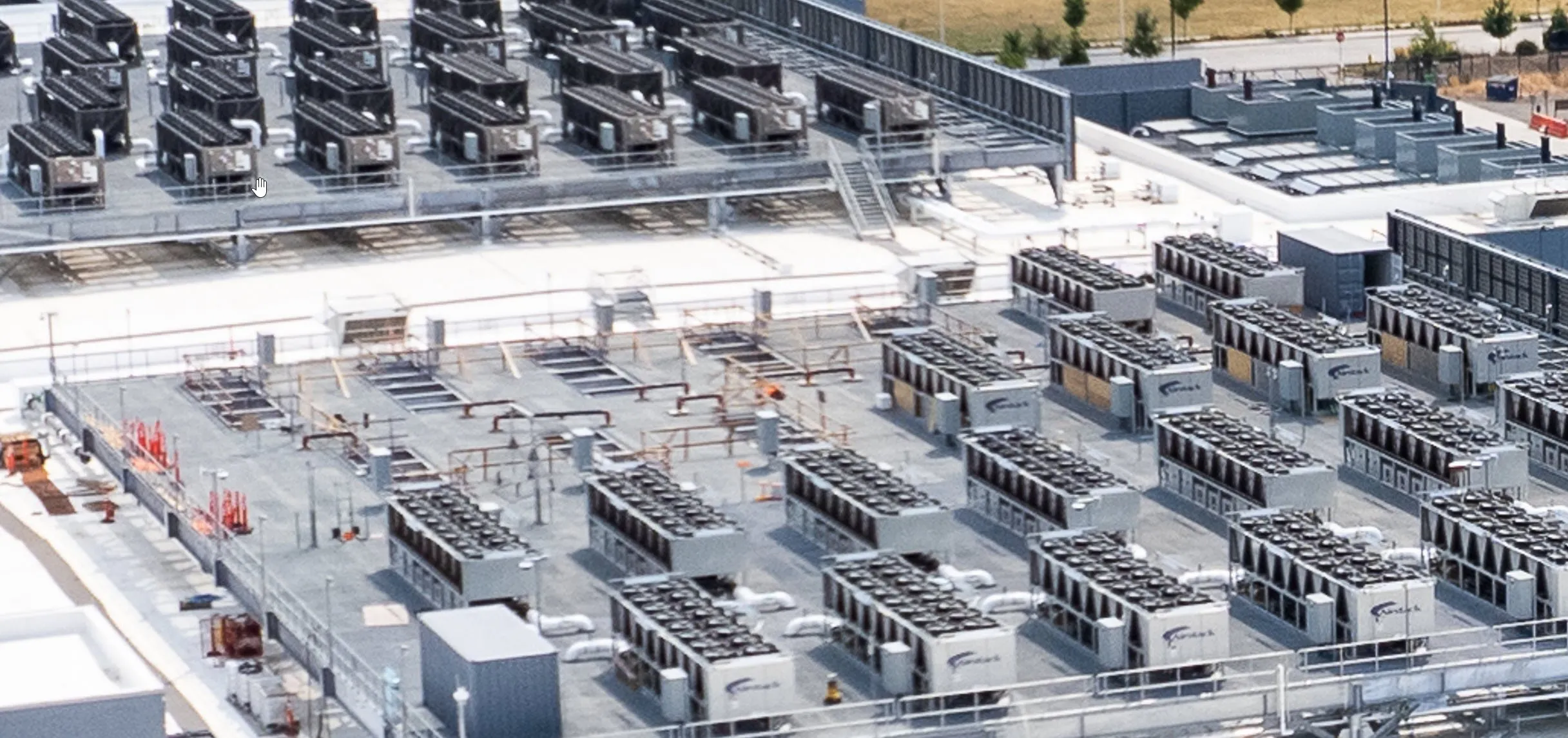 Aerial view of a massive data center campus rooftop covered in rows of cooling units across a large flat membrane roof