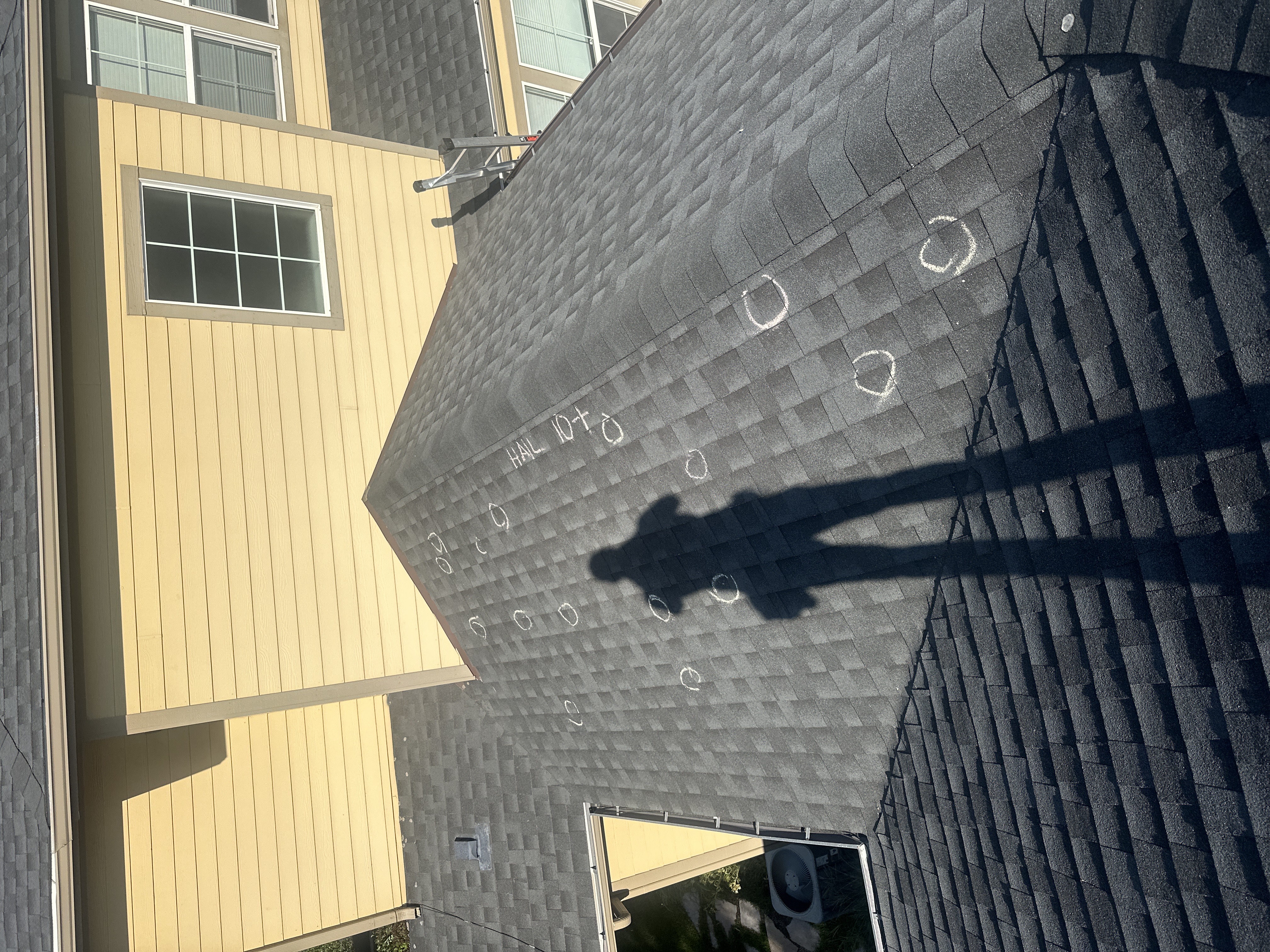 Force 5 Roofing inspector documenting circled hail strikes on a Denver Metro home