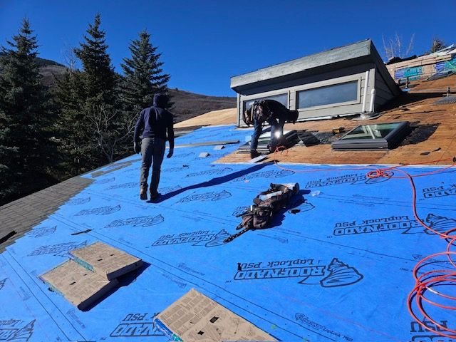 Force 5 Roofing crew laying ice & water shield underlayment around a skylight on a mountain home, fresh decking visible at the eaves