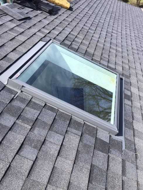 Newly installed skylight with fresh step flashing tying cleanly into the shingle field